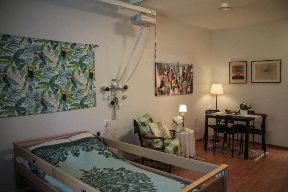 Mysigt inrett rum med säng, fåtölj och bord med stolar