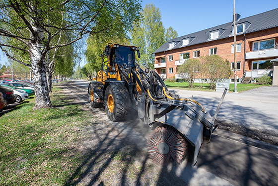 Traktor sopar sand, träd, hus