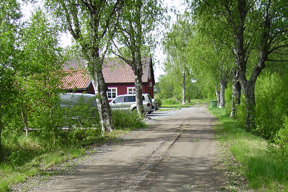 En grusväg som går fram till ett hus.