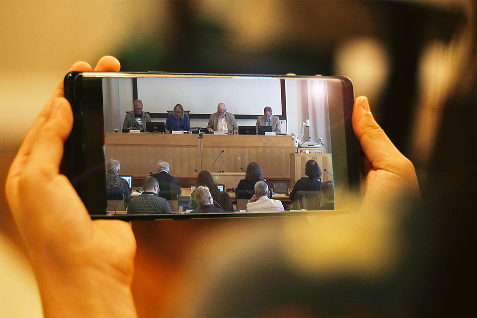 Kommunfullmäktiges presidium visas på en mobilskärm.