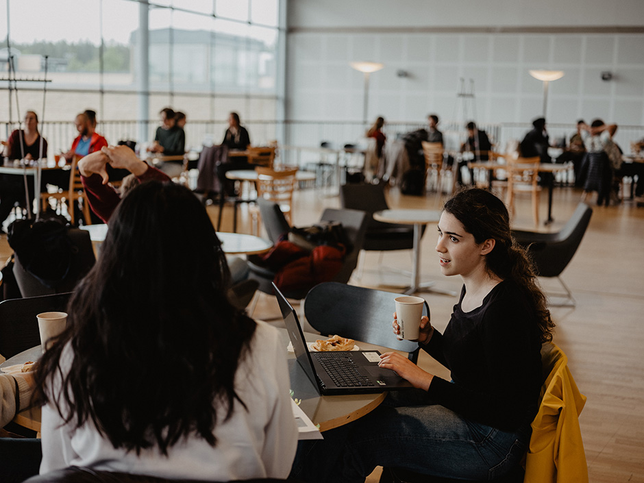 Två personer sitter på ett café på universitetsområdet.