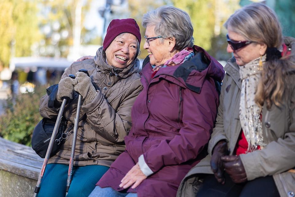 Vänner på en bänk som ler mot varandra