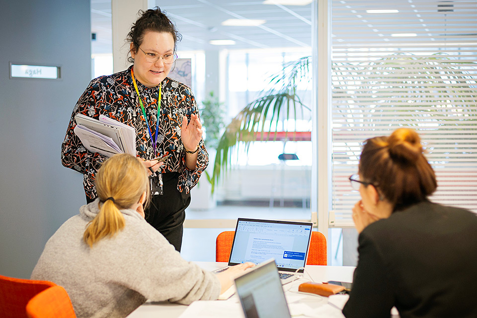 Stabsarbete under krisövning: En kvinna talar till två andra kvinnor vid ett bord.