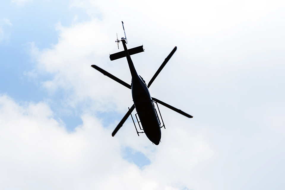 Flygande helikopter fotograferad underifrån mot molnig himmel