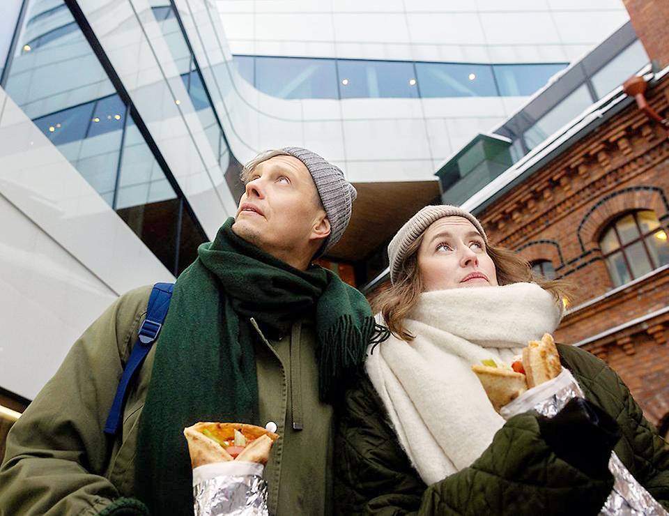 En man och kvinna äter rullpizza utanför Väven.
