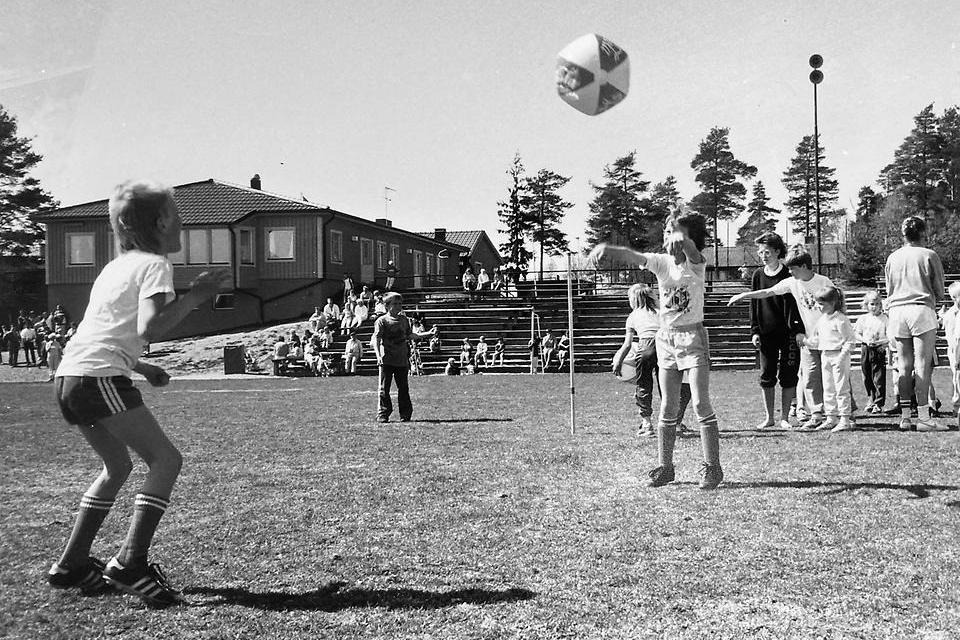 Ungdomsfotboll på Gimoborgs idrottsplats, föreningens kanslibyggnader syns i bakgrunden. Gimonäs CK arkiv, Folkrörelsearkivet i Västerbotten.