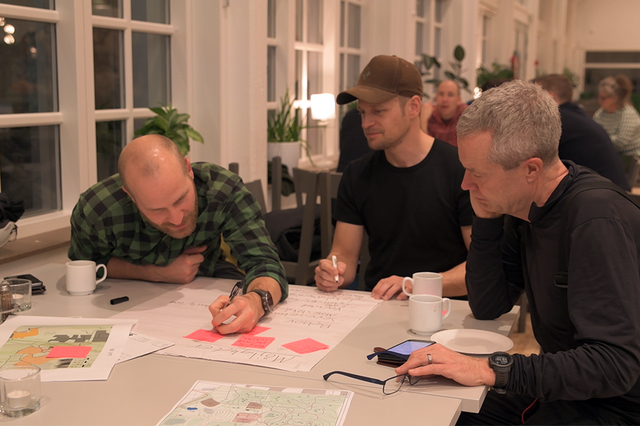 Fotografi från workshop med föreningar. På bilden syns tre personer som samtalar vid ett bord och skriver noteringar på ett blädderblock.