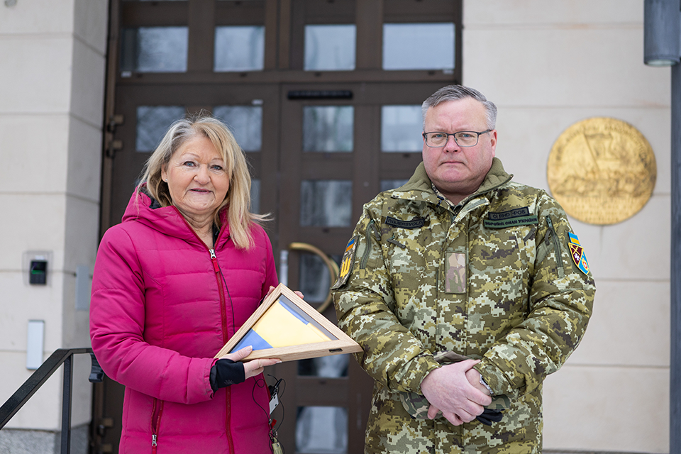 Marie-Louise Rönnmark tar emot en ukrainsk flagga från Peter Gjersvold vid stadshusets entré.