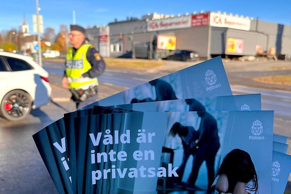 Bild med en polis i bakggrunden och broschyer förgrunden som det står "Våld är inte en privatsak"-