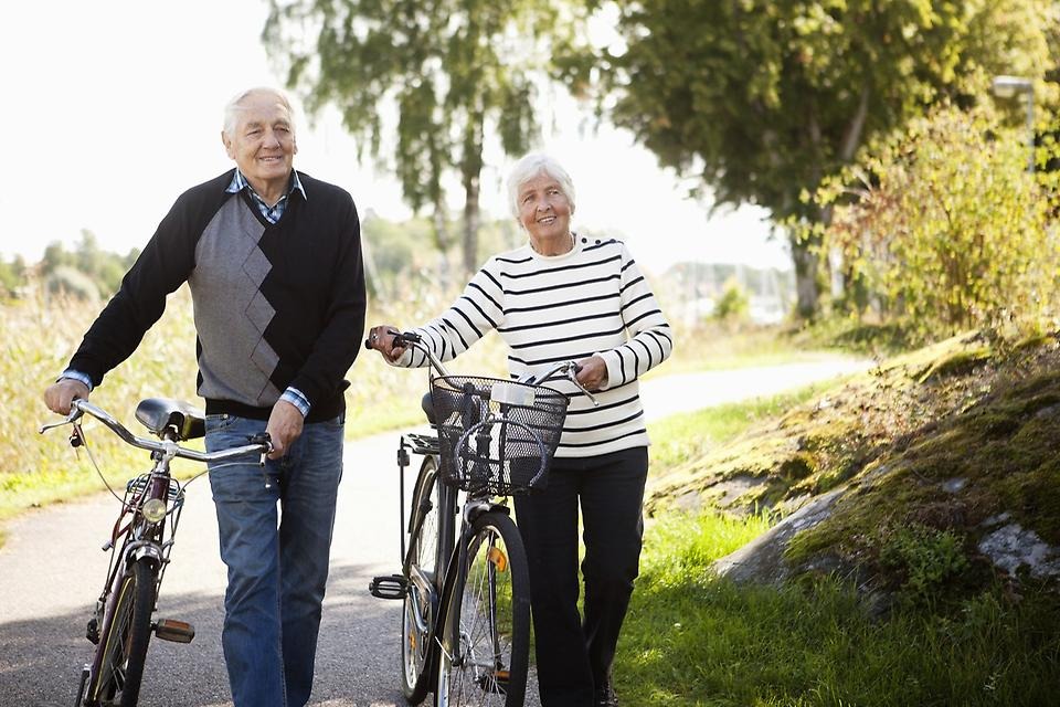 Kvinna och man som styr sina cyklar i somrig miljö.