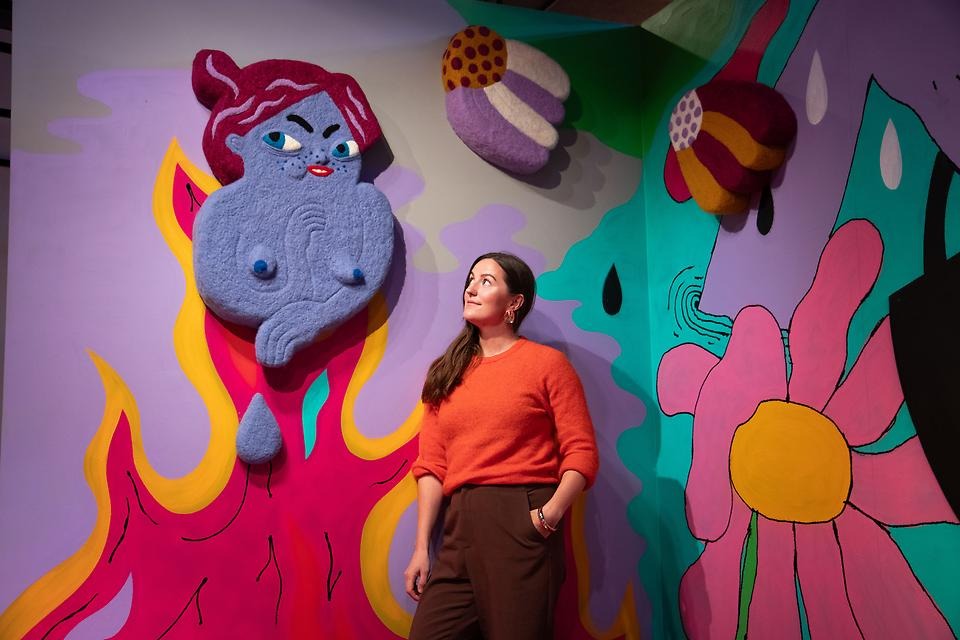 Sara Edenius står framför färg- och formstark konstinstallation.