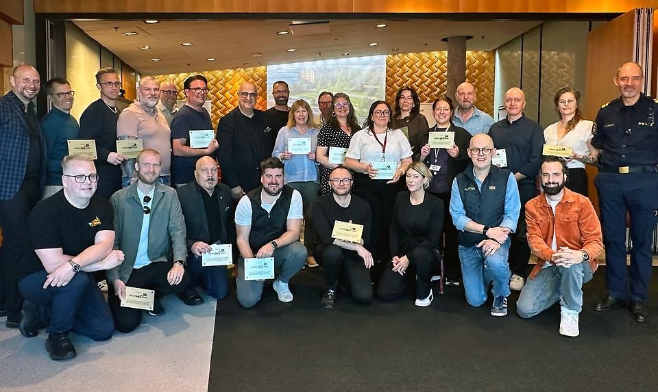 Grupp av människor som håller upp guldplaketter innomhus.