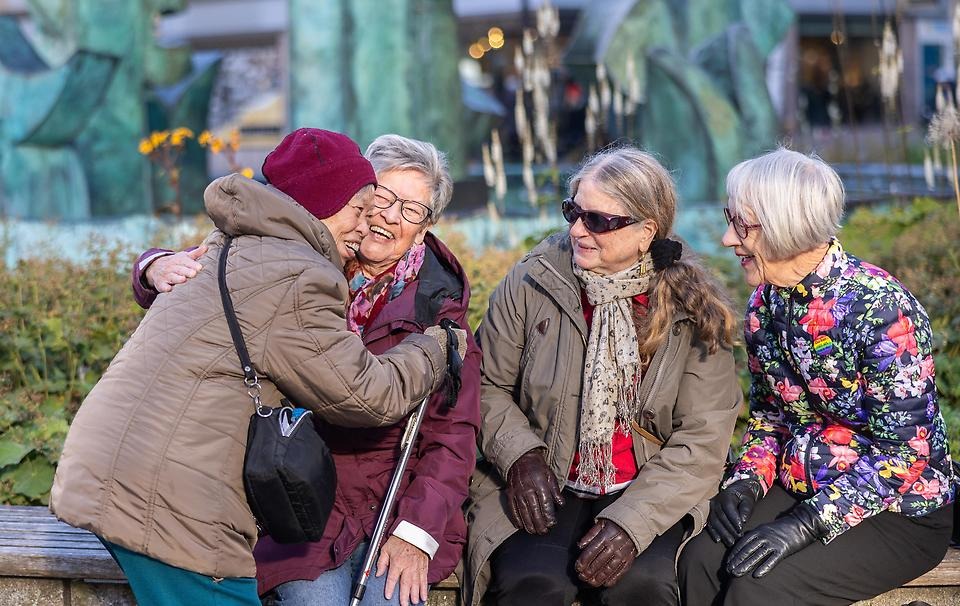 Vänner som träffs och hälsar på varandra, två av dem kramas