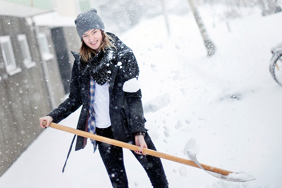 Ung kvinna skottar snö.