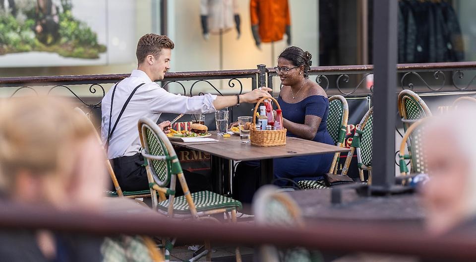 Ett par sitter utomhus på en restaurang och äter.