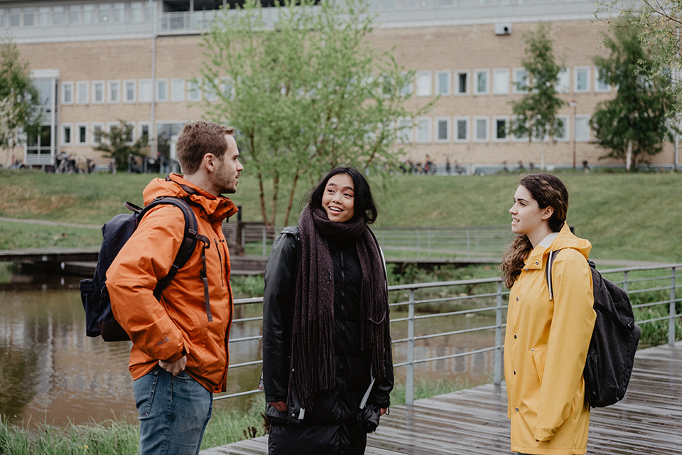 Tre studenter samtalar utanför Lindellhallen, Campus Umeå.