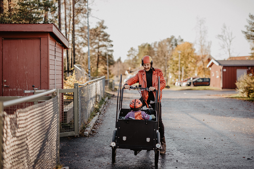 Bilden visar en pappa som lämnar barn på förskola med en lådcykel.