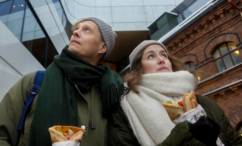 En man och en kvinnas äter rullkebab utanför Väven, Umeå.