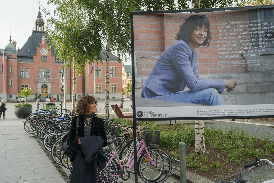 Nobelpristagaren Emmanuelle Charpentier i Umeå framför rådhuset och en budkapsposter som handlar om hennes forskningsinsatser.