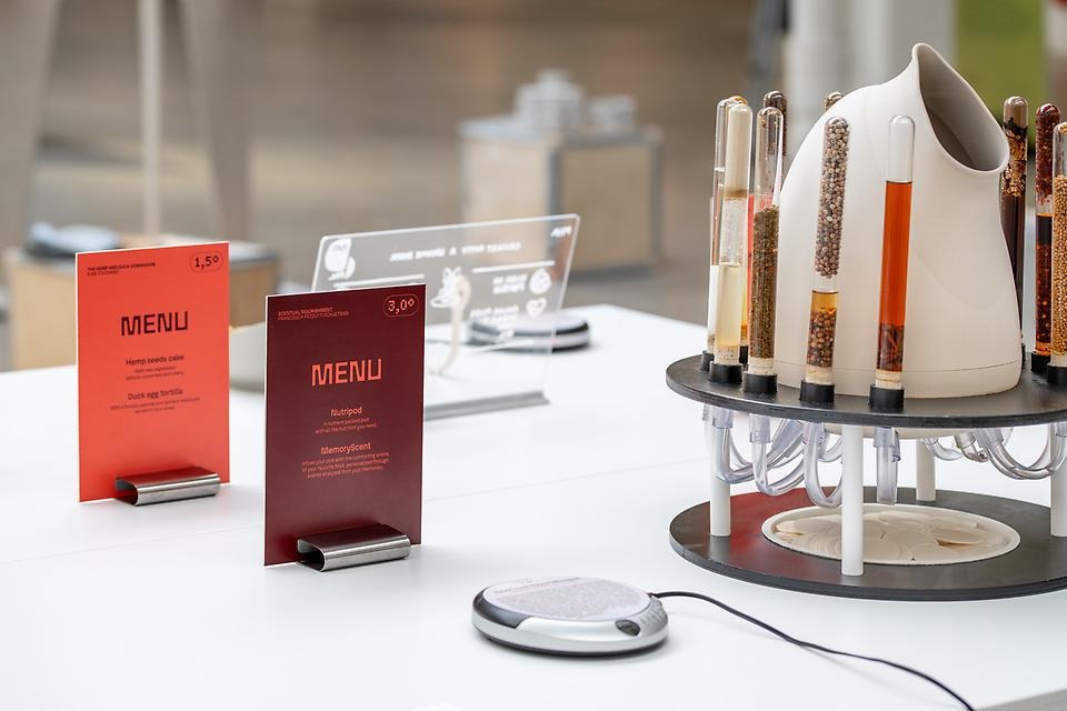 Ett vitt bord med röda meny­kort och en apparat med provrör fyllda med olika ingredienser.