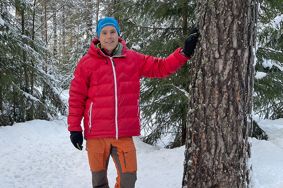 Johan Sandberg står lutad mot ett träd i I20-skogen. 