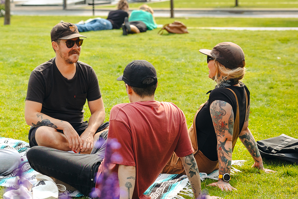 Vänner som sitter på en filt i en park och umgås