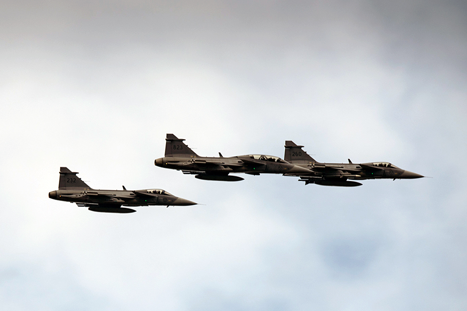 En grupp JAS 39 Gripen-flygplan i luften mot en grå himmel