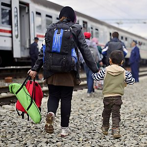 Kvinna och barn är på flykt och ska stiga på ett tåg.