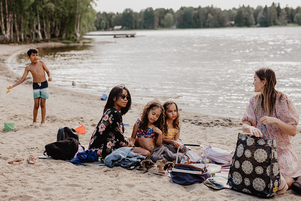 Vuxna och barn som badar och har picknick vid Nydalasjön.