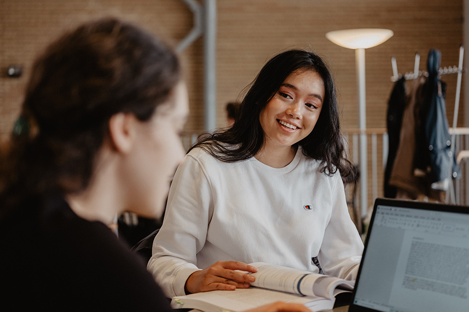 Två unga kvinnor studerar och har roligt vid Umeå universitet