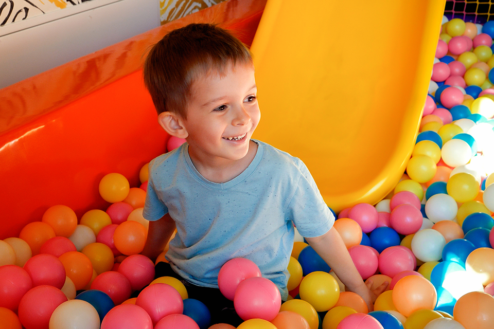 Ett barn som sitter i ett bollhav nedanför en rutschkana.