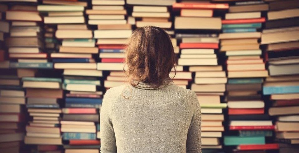 Kvinna med vägg av böcker