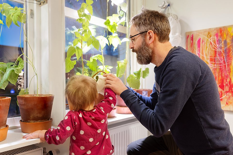 Litet barn på förskolan Gitarren får hjälp av personal att vattna krukor med plantor de odlar själva.