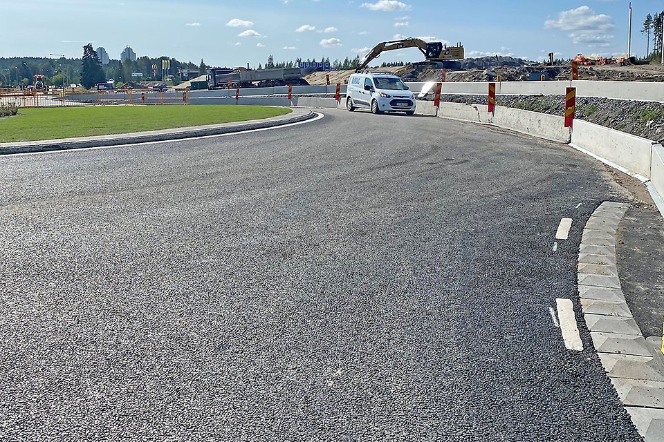 Bild på nylagd asfalt, med nymålade linjer, vid en rondell - där en vit bil står längre fram.