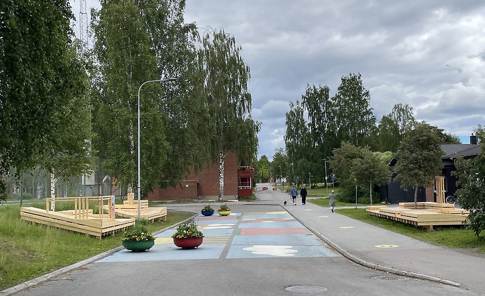 Bild av Socionomstråkets mittzon med möbler, gatumålning och blomsterurnor. Fotbollsplanen är till vänster i bild och Södra Ålidhemsskolan är till vänster i bild.