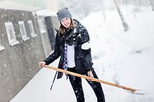 Ung kvinna skottar snö.