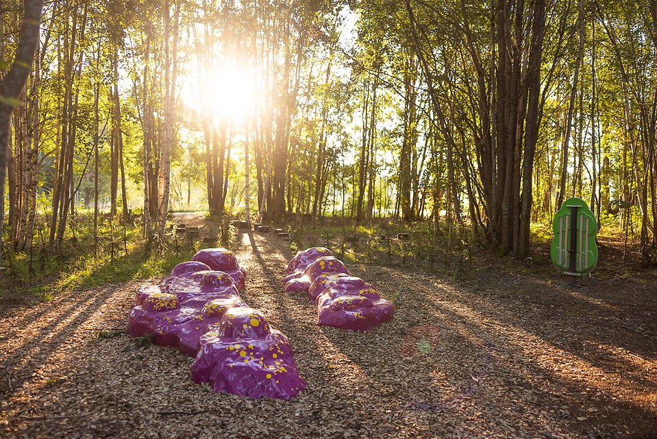 Ett lila konstverk i skogsglänta, skapad av barn. 